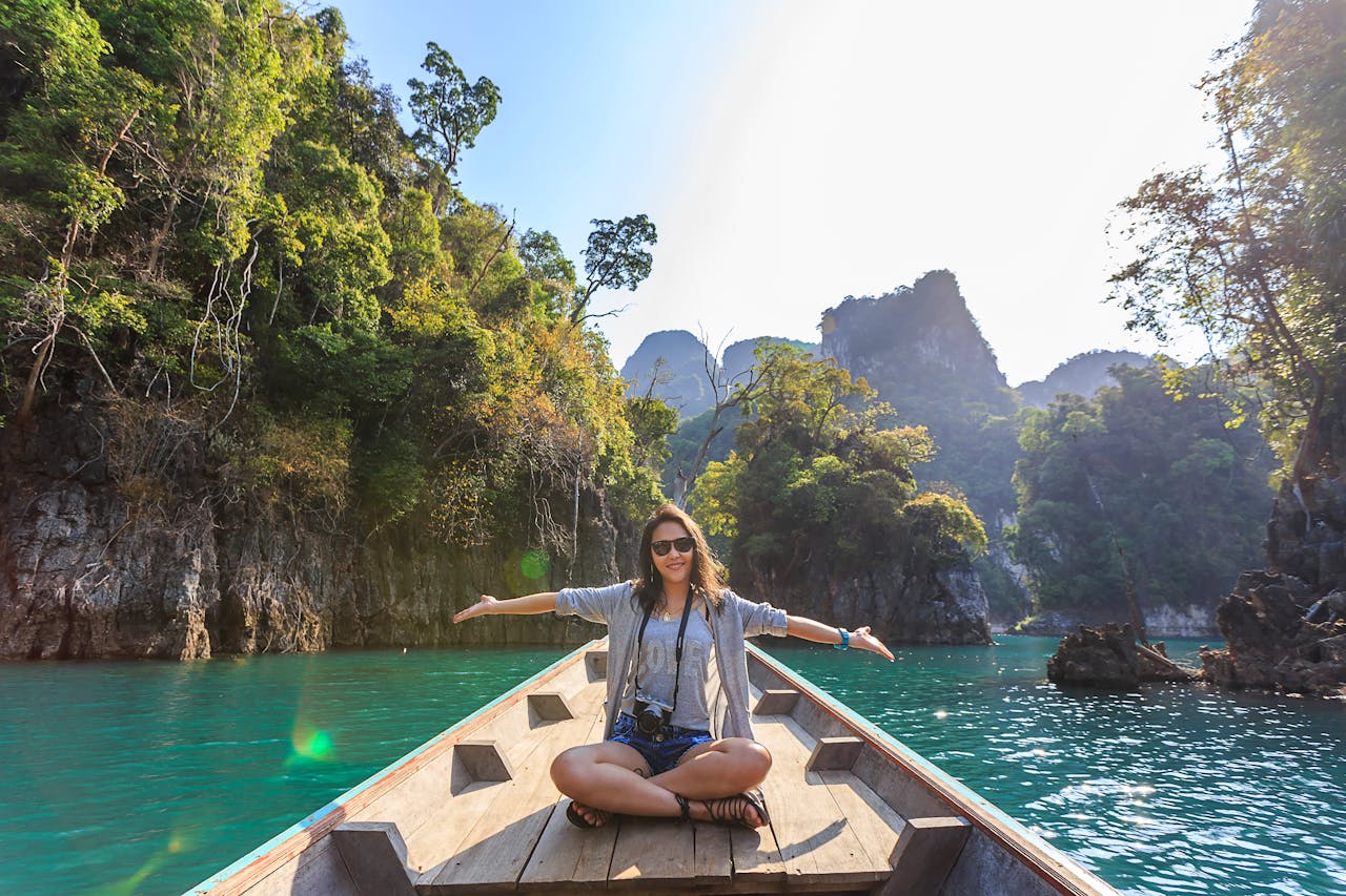 Services Asian woman relishing a serene boat journey through the lush karst landscape of Thailand's Khlong Sok.