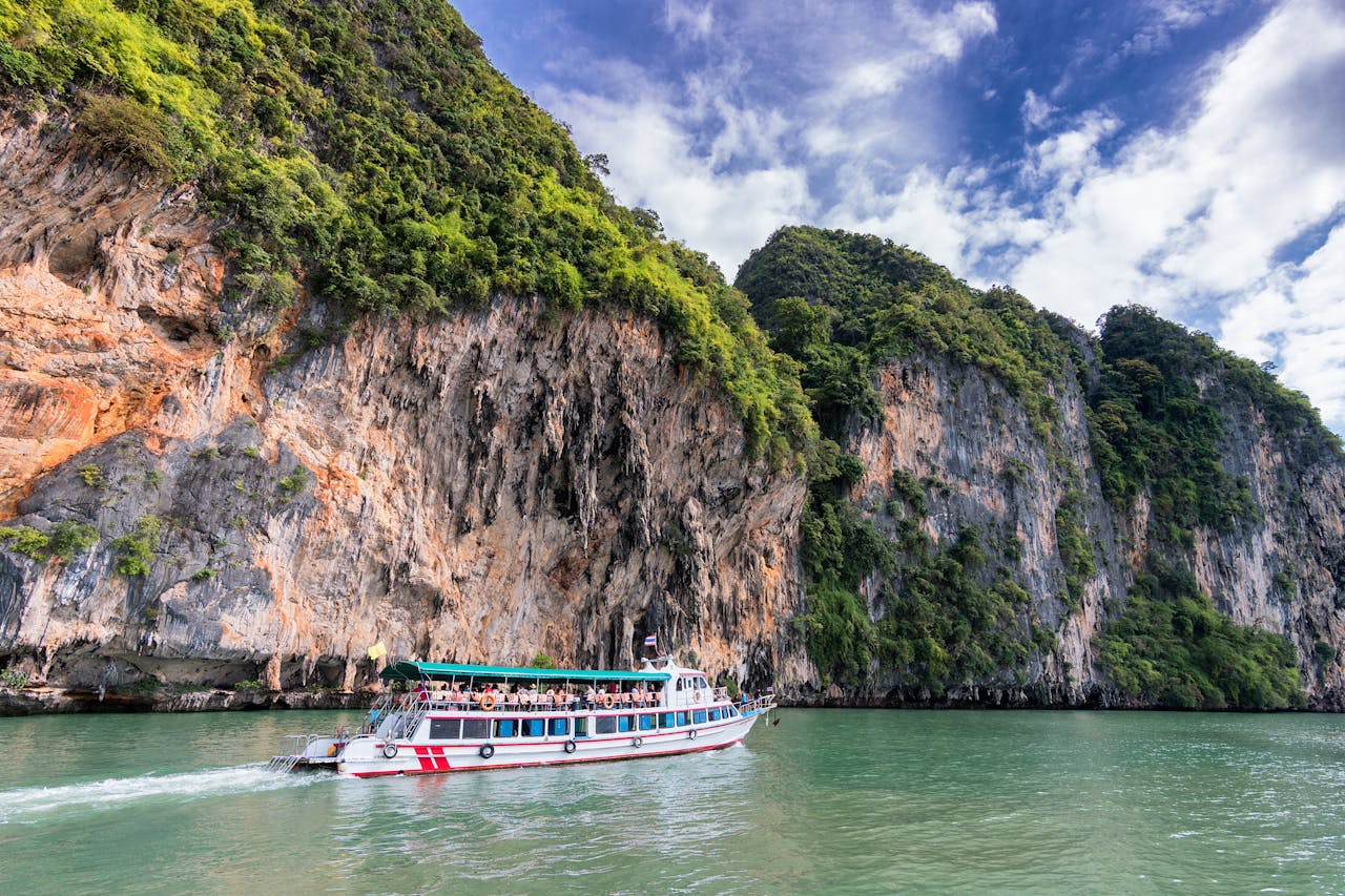Services A boat cruise offers breathtaking views of lush cliffs under a bright blue sky.