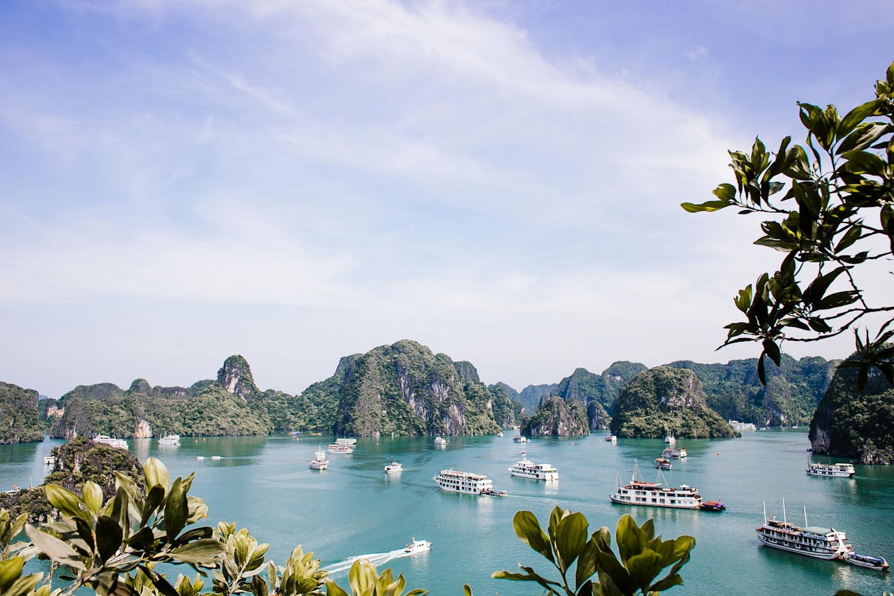 Home Serene Halong Bay vista featuring iconic limestone islands and boats under a clear sky.